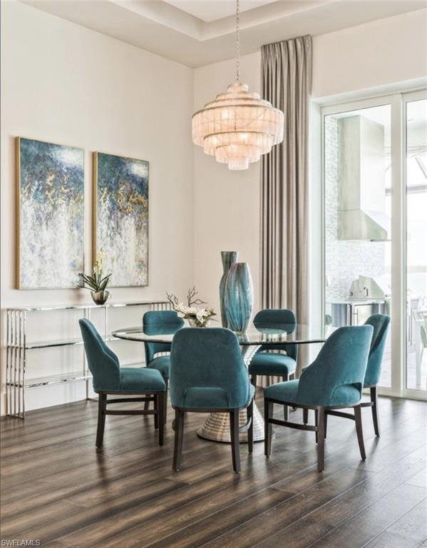 Dining area with dark wood finished floors, a chandelier, and a raised ceiling