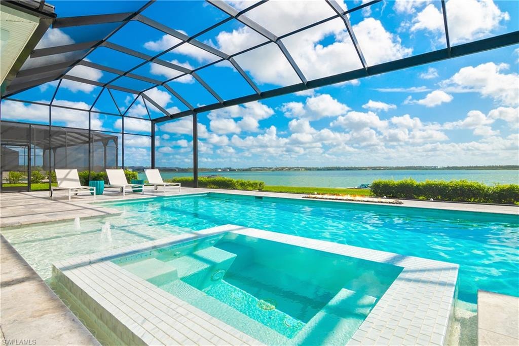 View of pool with glass enclosure, a pool with connected hot tub, a sunroom, a patio area, and a water view