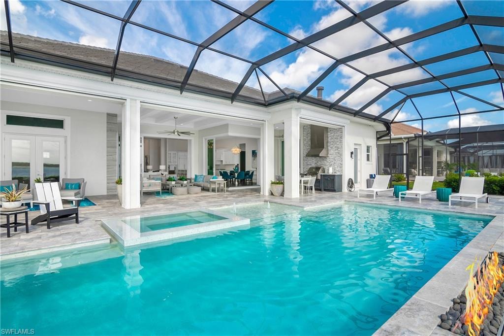 View of pool featuring a patio area, a lanai, a sunroom, an outdoor living space, and a pool with connected hot tub