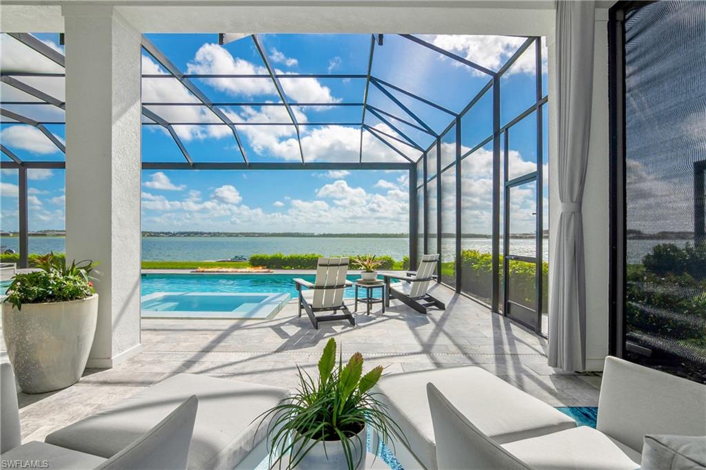 Outdoor pool featuring a sunroom, glass enclosure, a patio area, and a water view