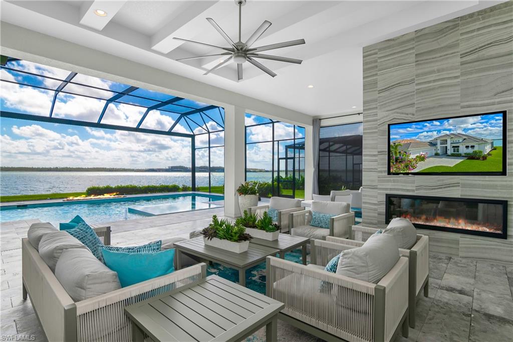 View of patio / terrace featuring a sunroom, ceiling fan, an outdoor pool, glass enclosure, and an outdoor living space with a fireplace