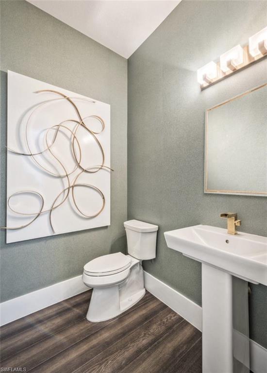 Bathroom with dark wood-style flooring and a textured wall