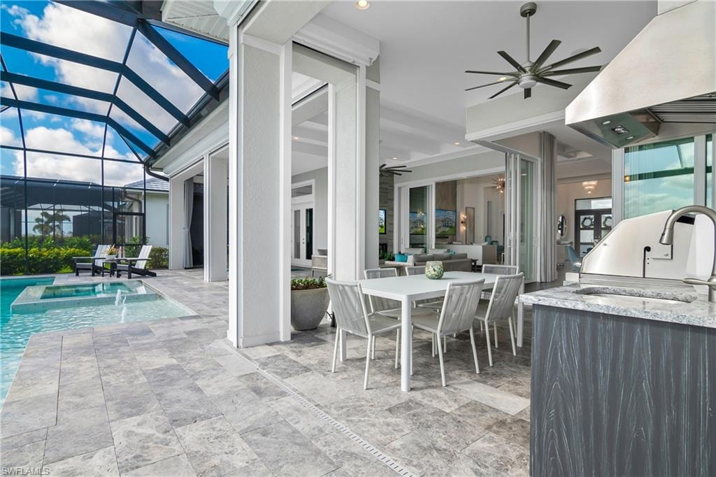 View of patio featuring ceiling fan, glass enclosure, outdoor dining space, a sunroom, and a pool with connected hot tub