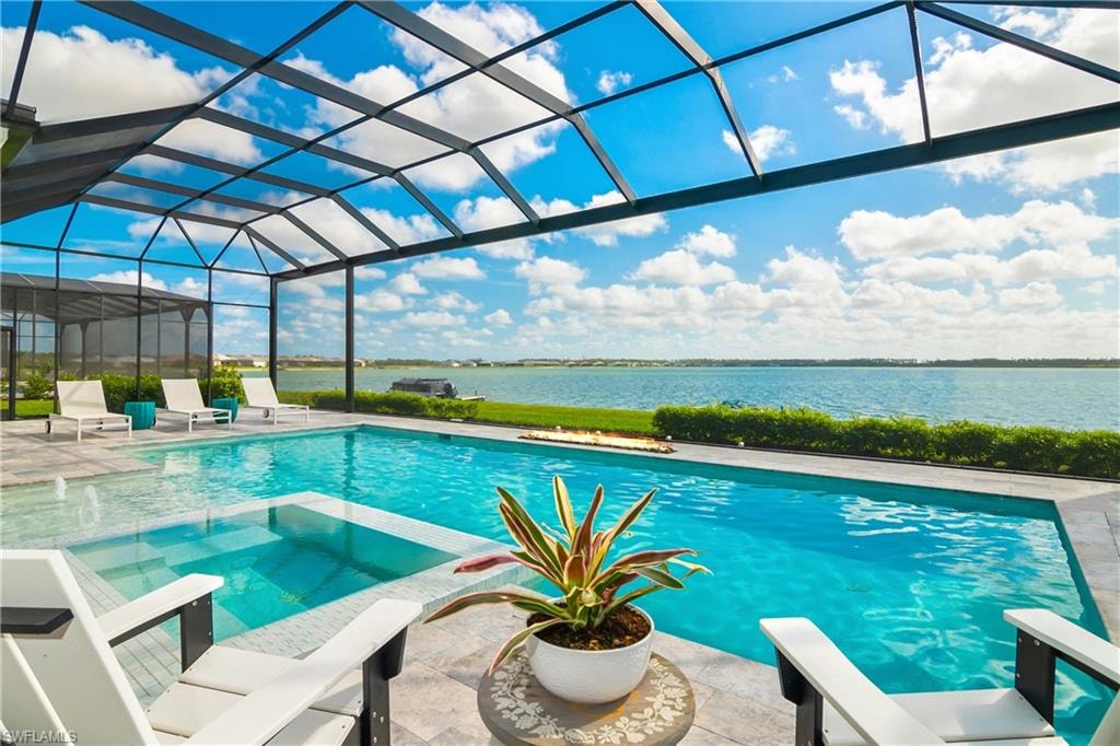 View of pool with a lanai, a sunroom, a patio area, a water view, and a pool with connected hot tub
