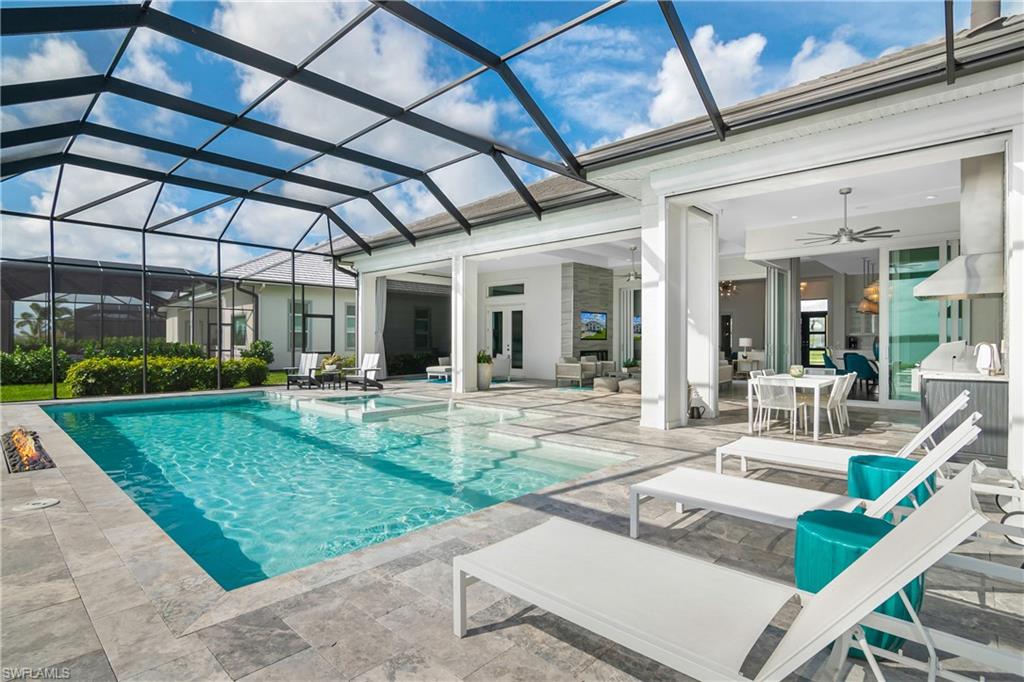 View of pool with glass enclosure, a patio area, a sunroom, a pool with connected hot tub, and outdoor dining space