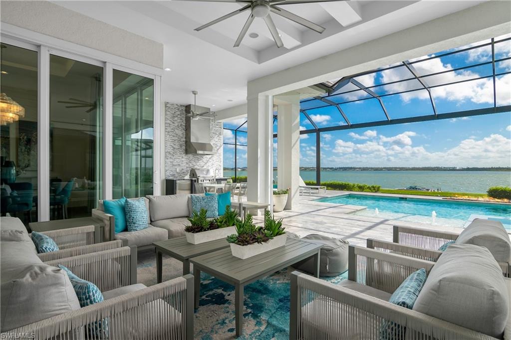 Swimming pool with an outdoor living space, a lanai, a patio area, and a water view
