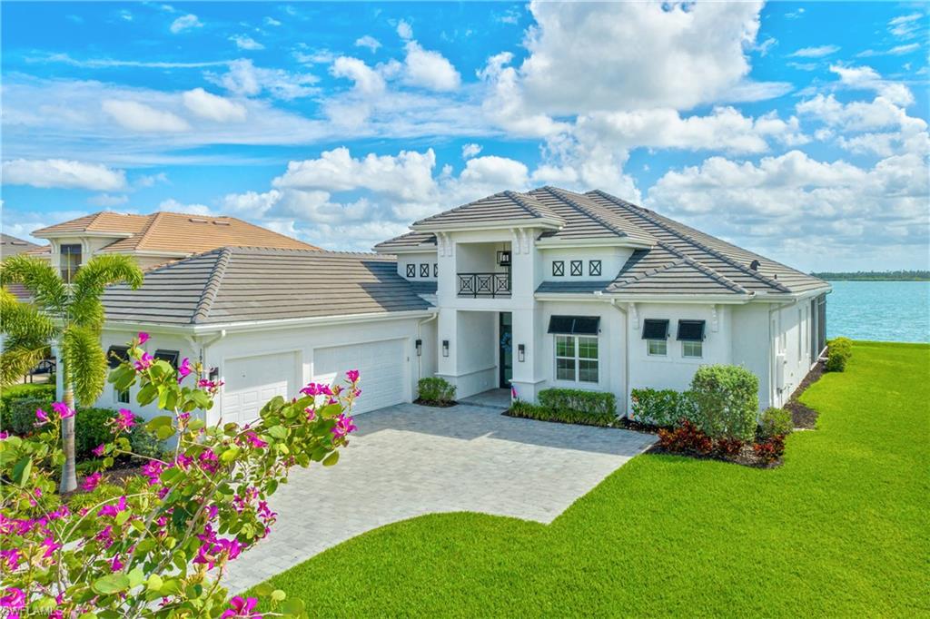 View of front of home with a garage, a front yard, decorative driveway, stucco siding, and a tile roof