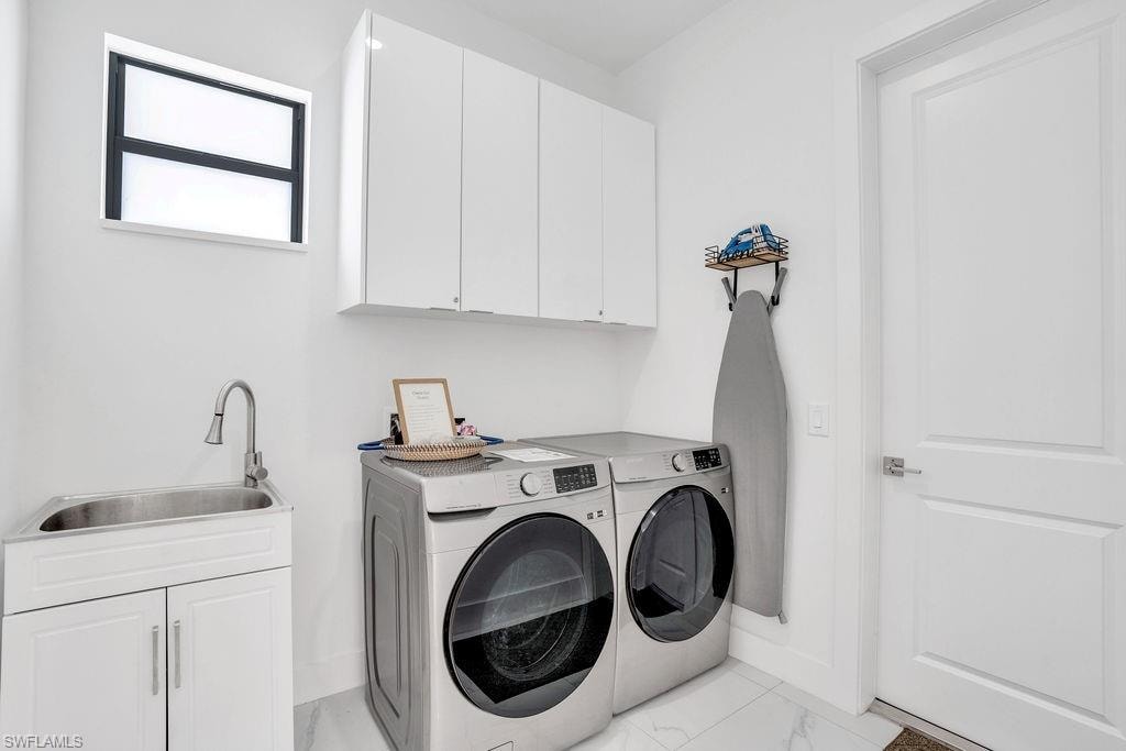 Laundry area with cabinet space, light marble finish flooring, and washing machine and dryer