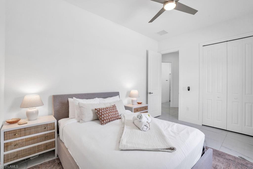 Bedroom with ceiling fan, a closet, and light marble finish flooring