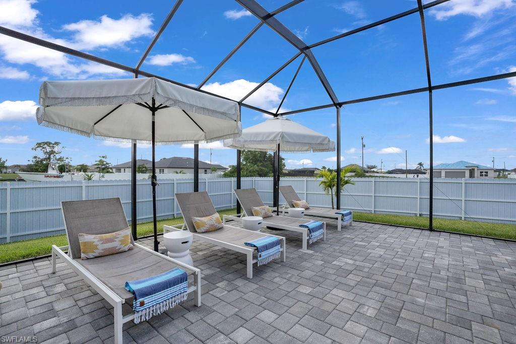 Fenced backyard featuring cage enclosure, a patio, and a sunroom