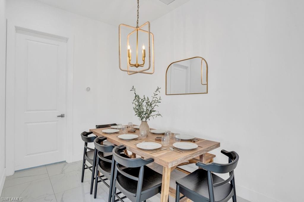 Dining room with light marble finish flooring and a chandelier