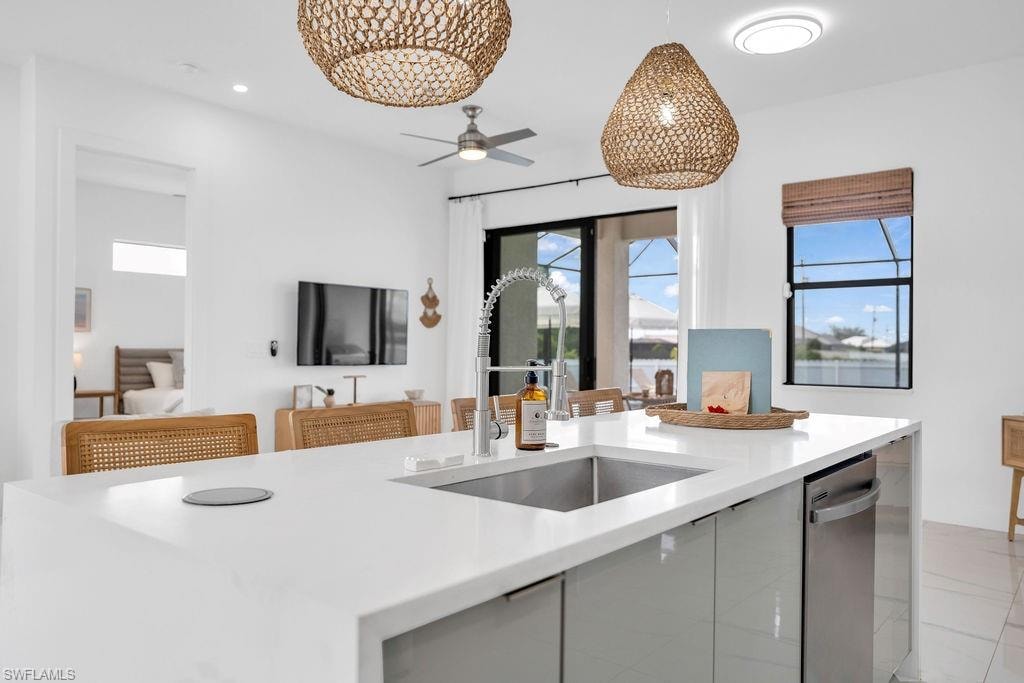 Kitchen featuring modern cabinets, light stone countertops, hanging light fixtures, ceiling fan, and recessed lighting