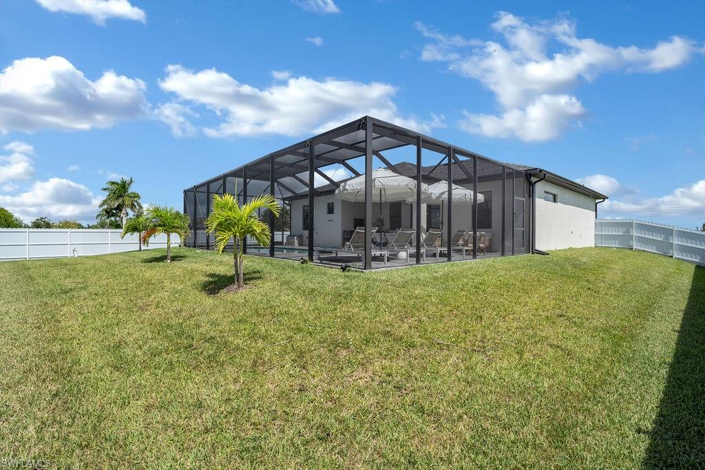Back of house with a fenced backyard, a lanai, a sunroom, and stucco siding