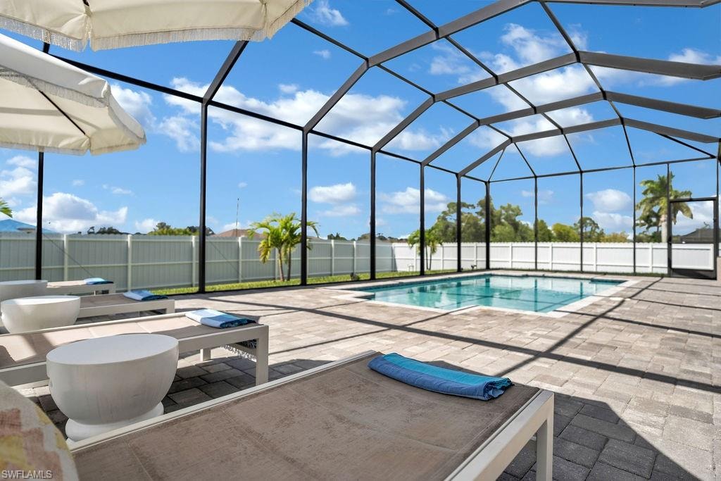 View of pool featuring a lanai, a fenced backyard, a sunroom, and a patio