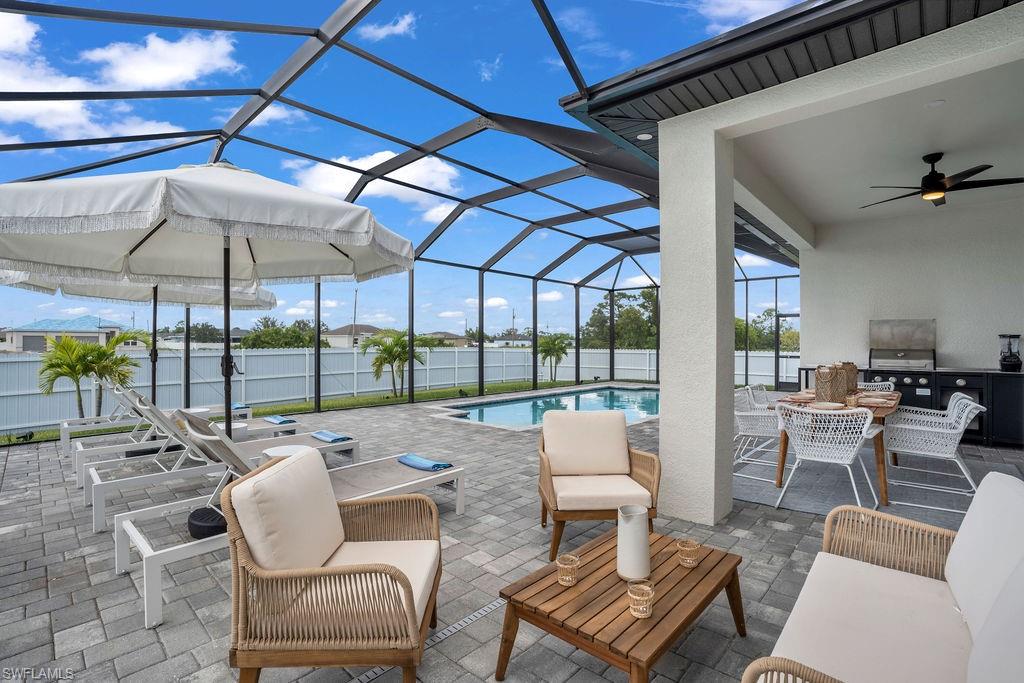 View of patio with a lanai, a ceiling fan, a sunroom, outdoor lounge area, and an outdoor kitchen