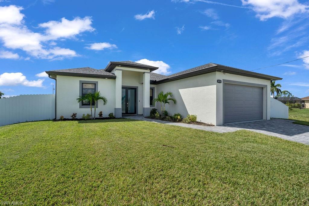 Ranch house featuring a garage, stucco siding, and paver driveway