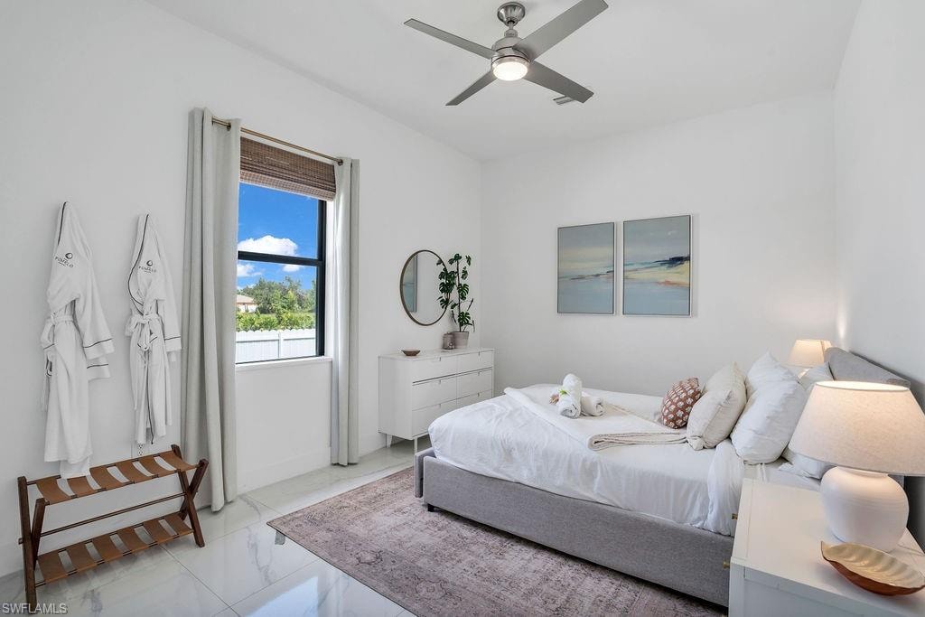 Bedroom with a ceiling fan and marble finish floors
