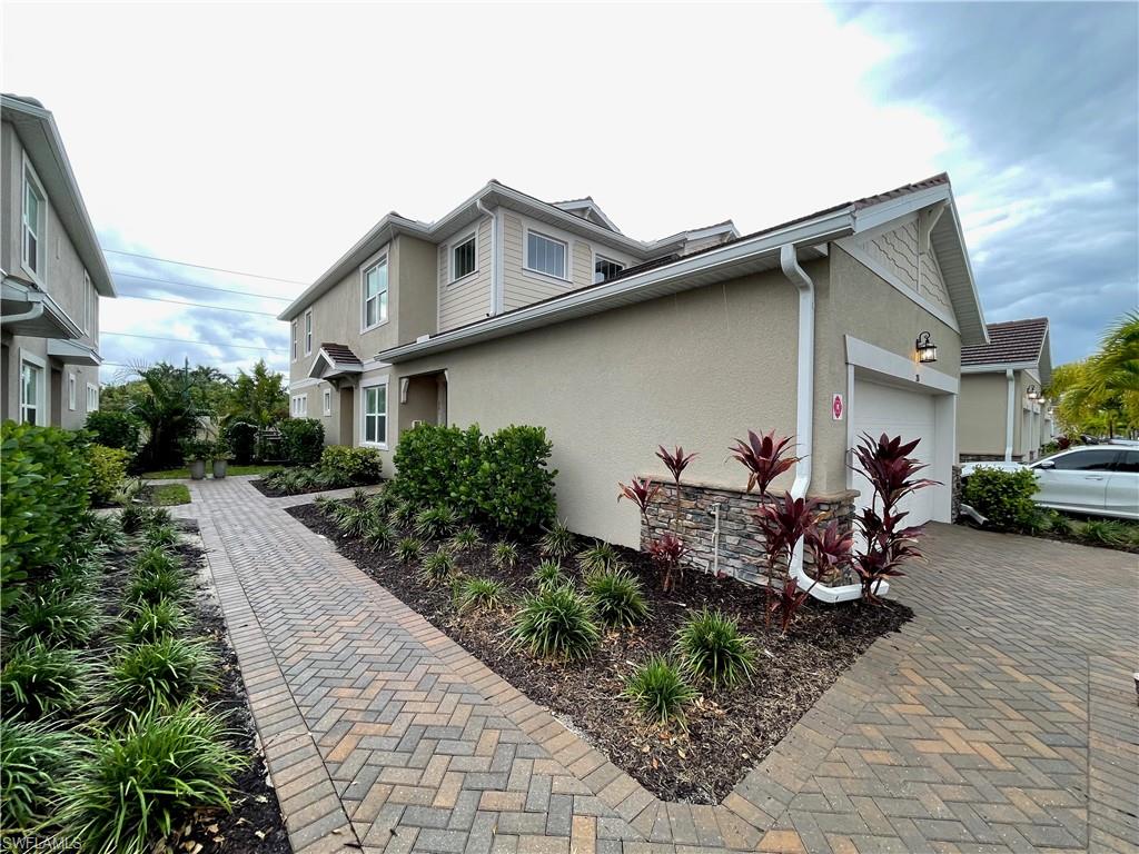 View of property exterior with stucco siding, a garage, and decorative driveway