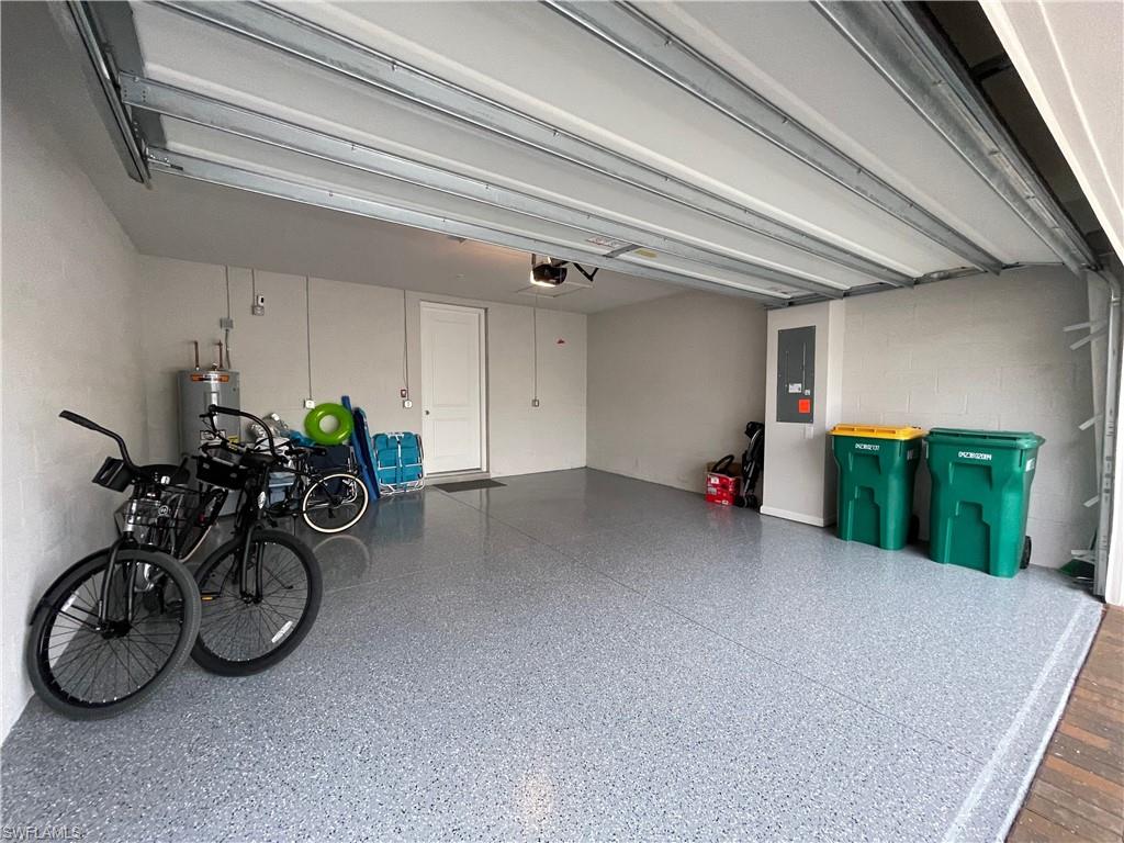Garage with concrete block wall, electric panel, and water heater