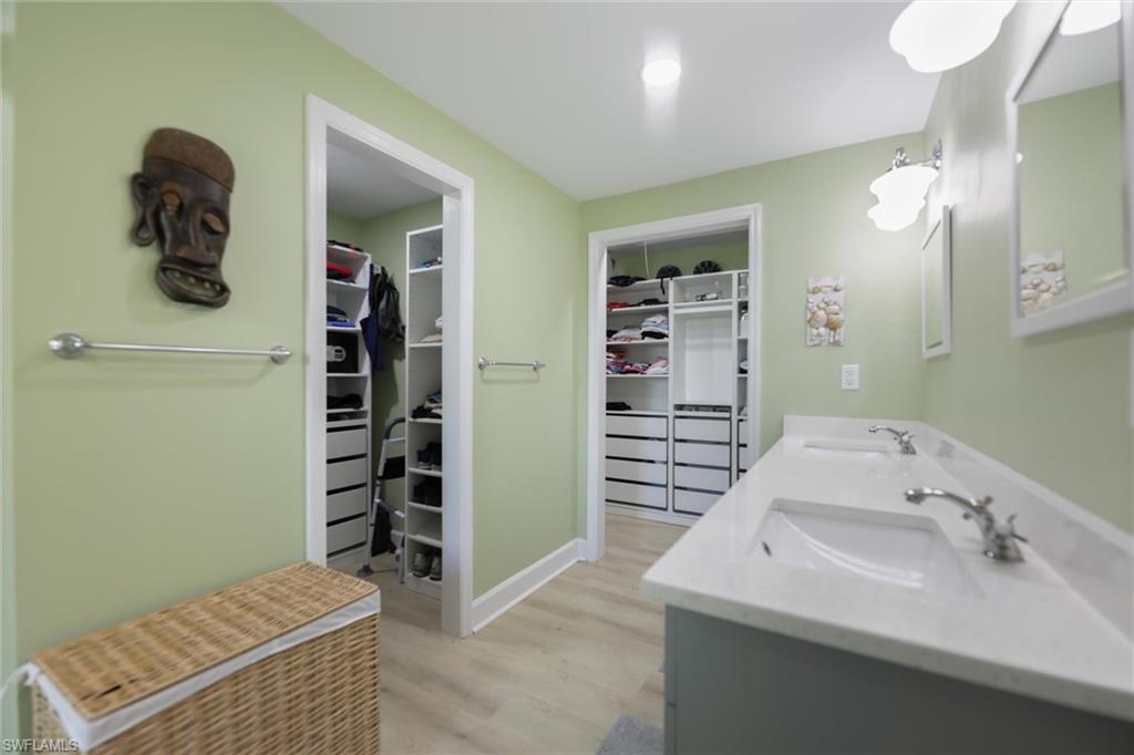 Full bathroom with two  spacious closets, light wood-style floors, and double vanity