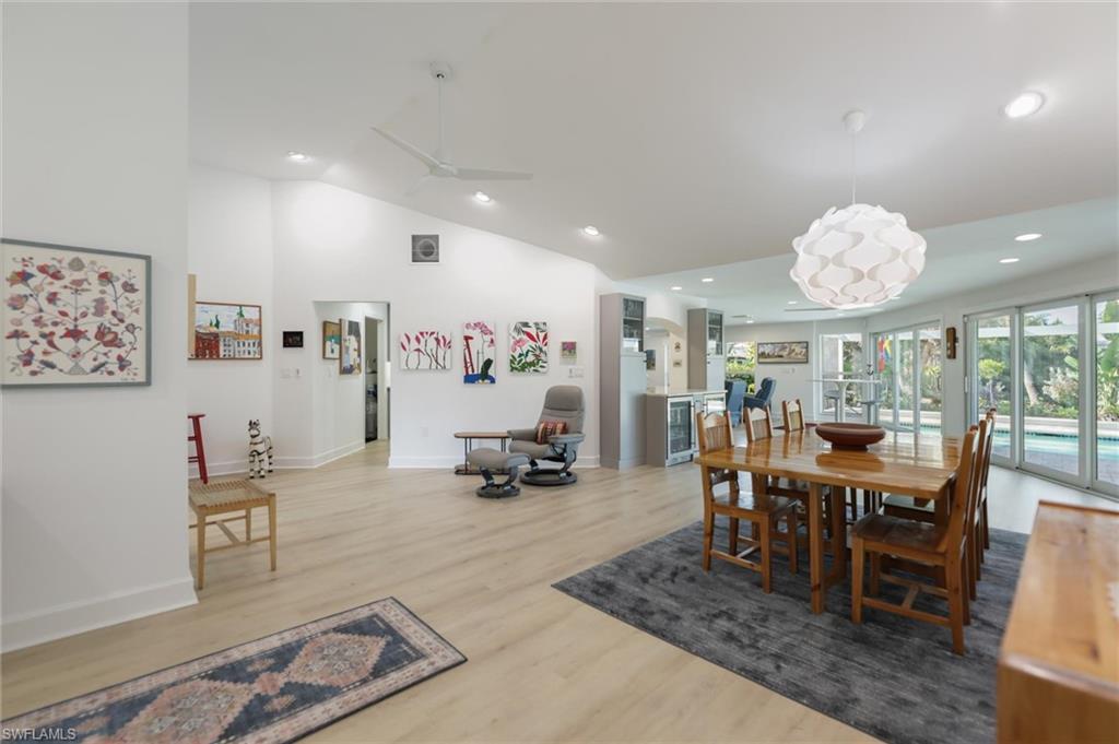 Dining area with lofted ceiling, light wood-type flooring, recessed lighting, wine cooler, and a ceiling fan