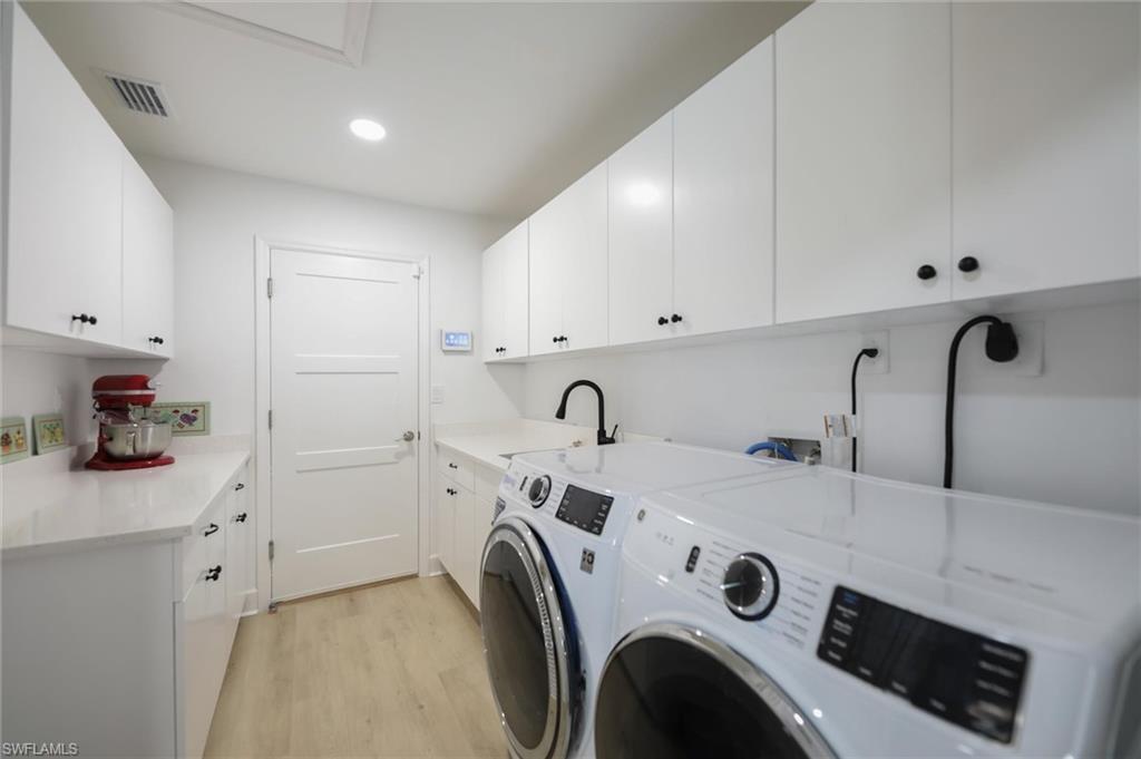 Laundry room featuring light wood-style flooring, washing machine and clothes dryer, cabinet space, and recessed lighting