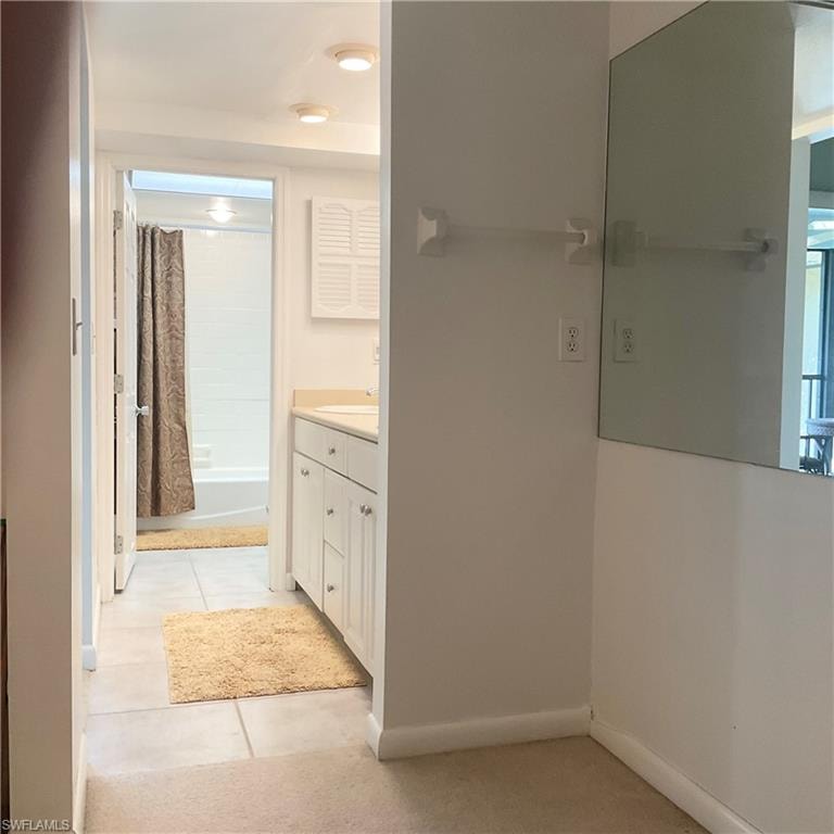 Primary bathroom with tile floors, vanity, and shower/tub. Primary has walk-in closet