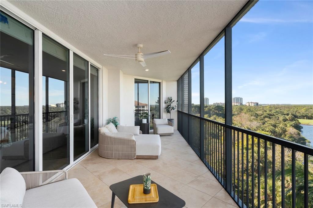 Sunroom with ceiling fan, expansive windows, a balcony, tile patterned flooring, and a textured ceiling