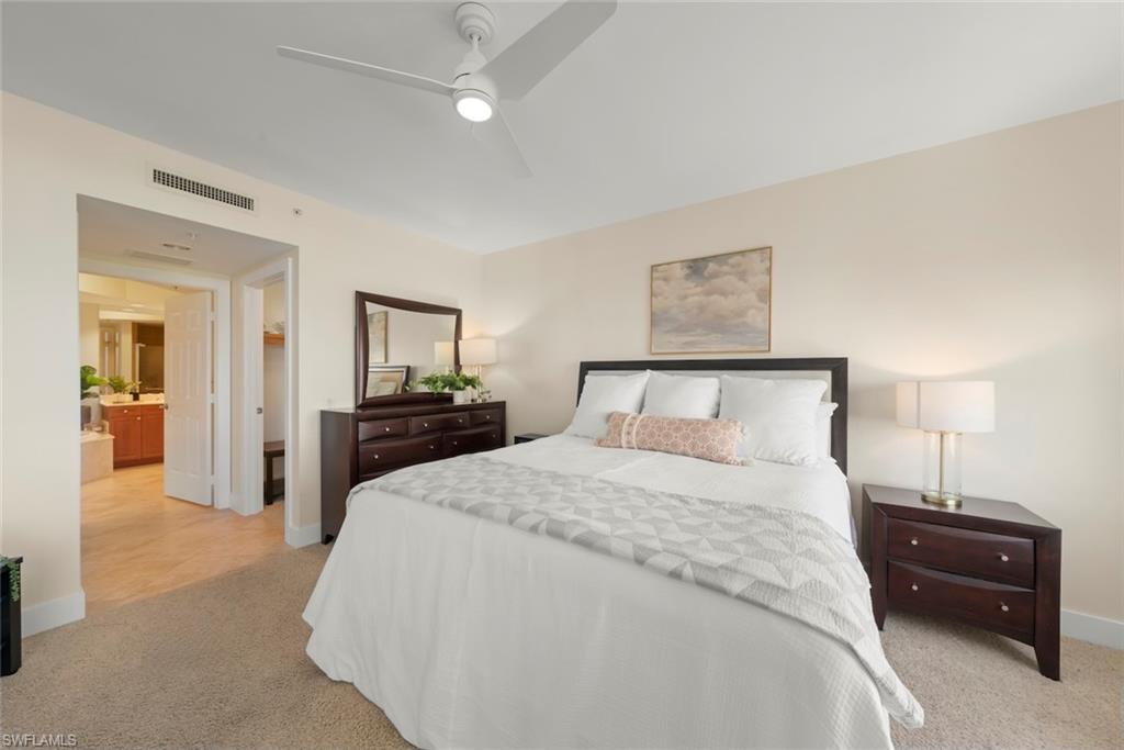 Bedroom with a walk in closet, light colored carpet, and ceiling fan