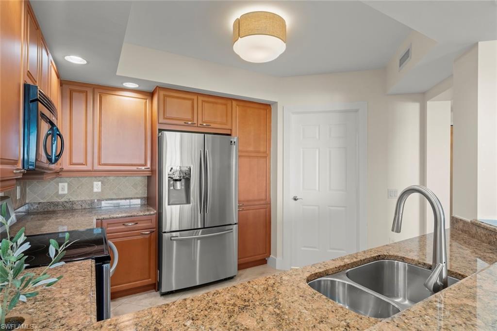 Kitchen featuring black appliances, light stone countertops, recessed lighting, light tile patterned flooring, and brown cabinetry