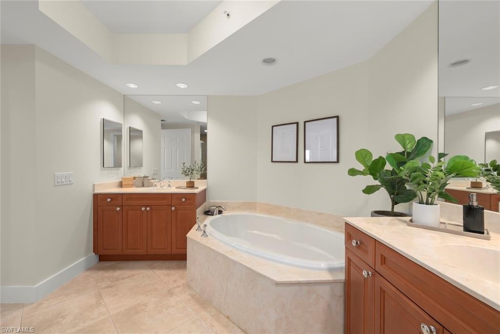Bathroom with a bath, two vanities, light tile patterned flooring, and recessed lighting