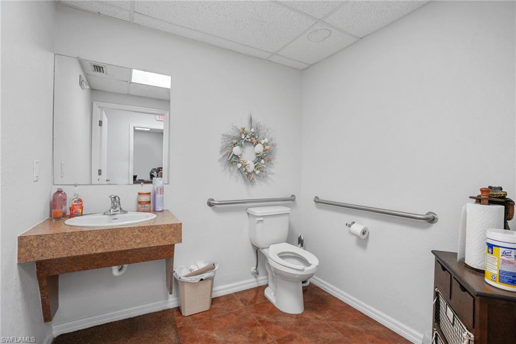 Half bath featuring dark tile patterned flooring, a paneled ceiling, and vanity