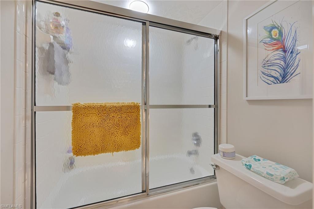 Bathroom featuring shower / bath combination with glass door and toilet