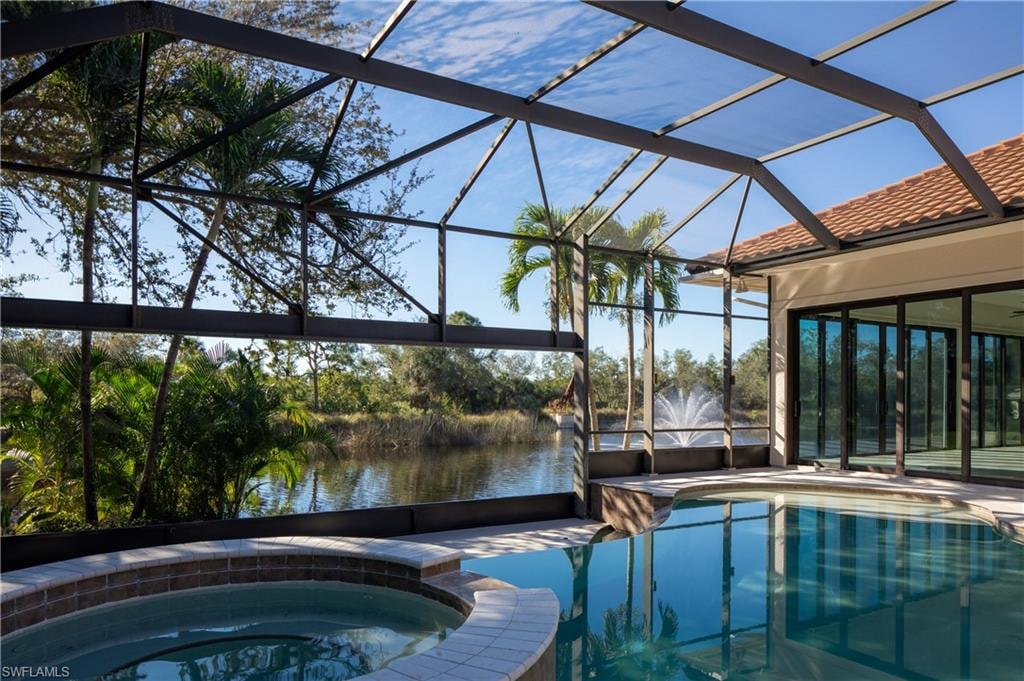 View of swimming pool with a sunroom, a pool with connected hot tub, a lanai, a patio area, and a water view