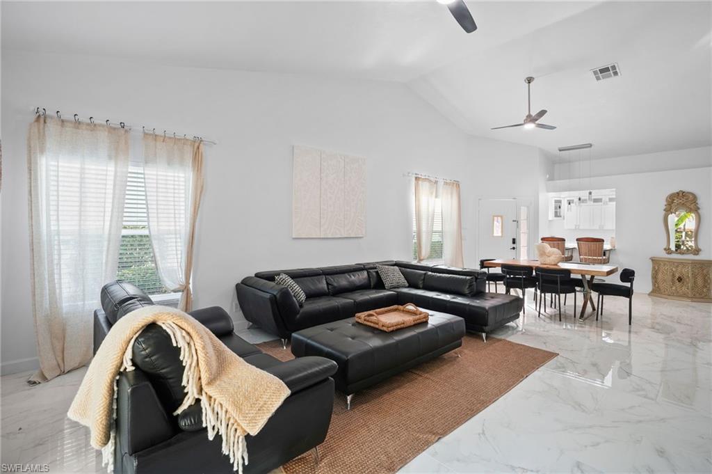 Living room featuring light marble finish floors, high vaulted ceiling, and ceiling fan