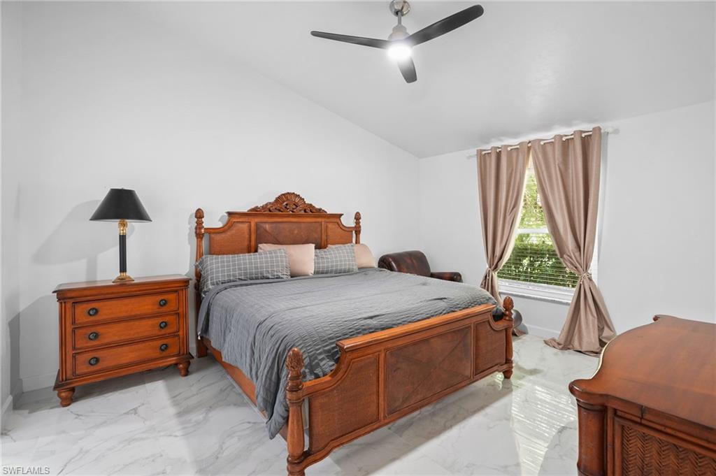 Bedroom featuring light marble finish floors, a ceiling fan, and lofted ceiling