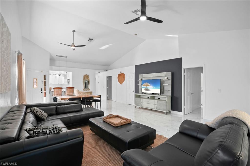 Living room with high vaulted ceiling, marble finish floors, and ceiling fan