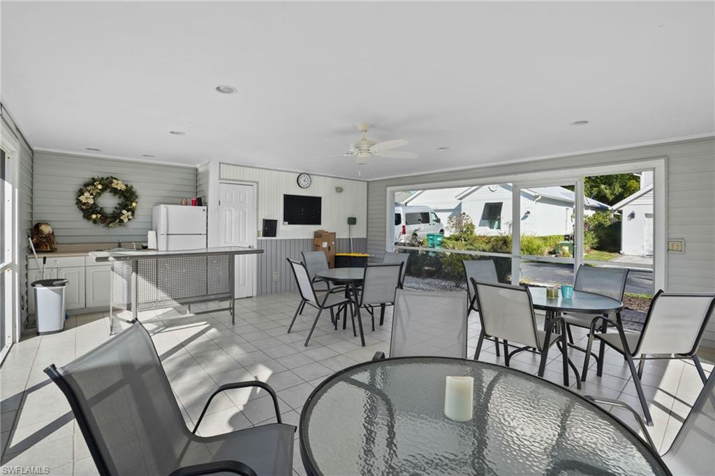 Dining area with a sunroom, wood walls, ceiling fan, and light tile patterned floors