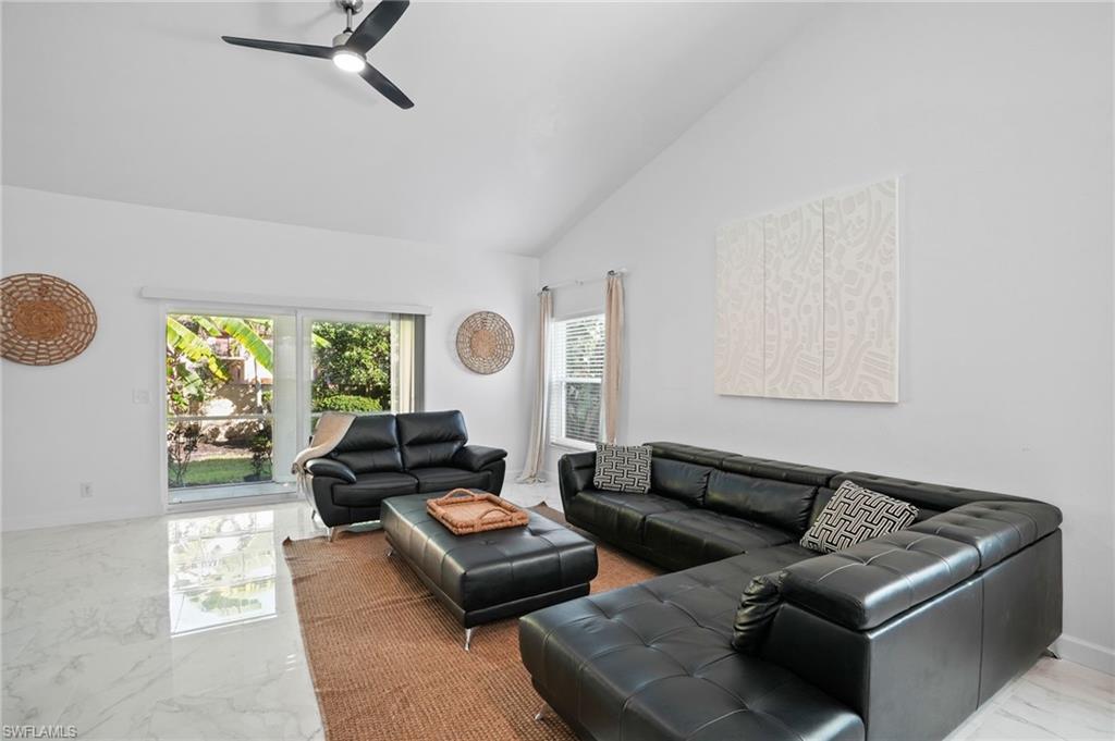 Living area with marble tiled floors, high vaulted ceiling, and a ceiling fan