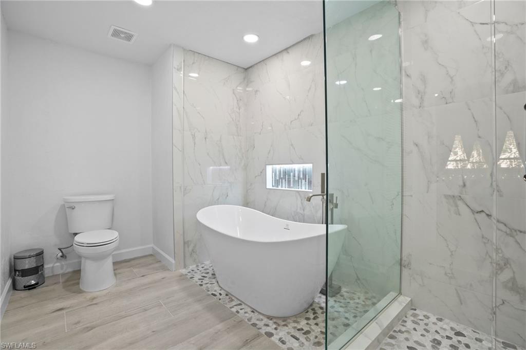 Bathroom with a soaking tub, a marble finish shower, wood tiled floors, recessed lighting, and tile walls