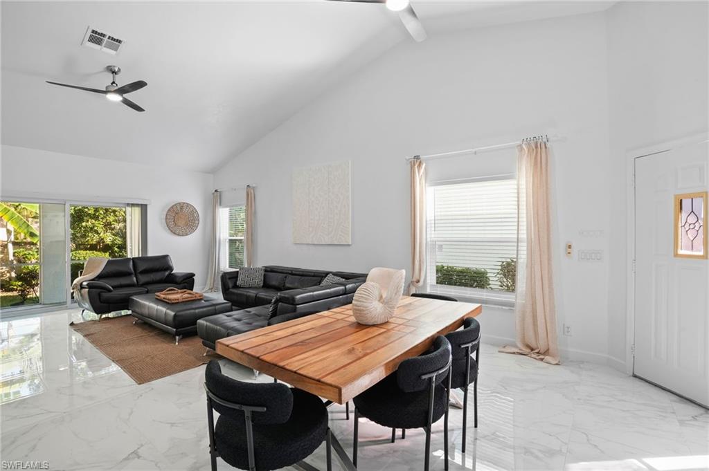 Dining space featuring high vaulted ceiling, ceiling fan, and light marble finish floors