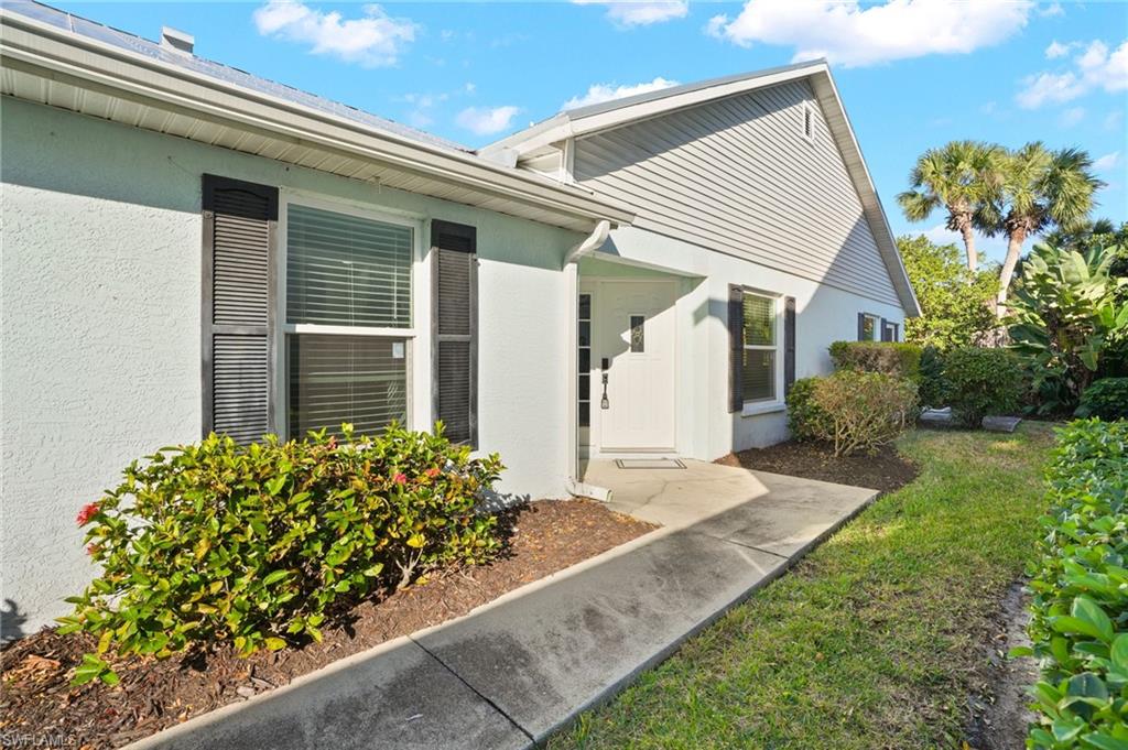 Property entrance with a yard and stucco siding