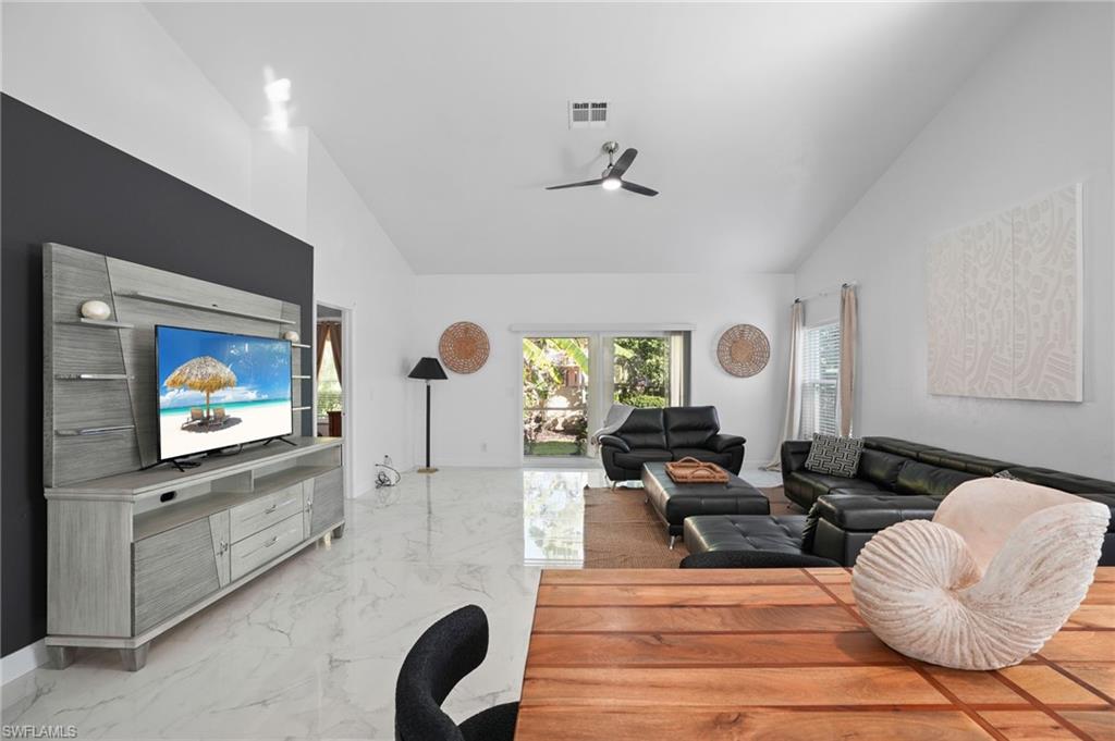 Living room with light marble finish flooring, high vaulted ceiling, and a ceiling fan