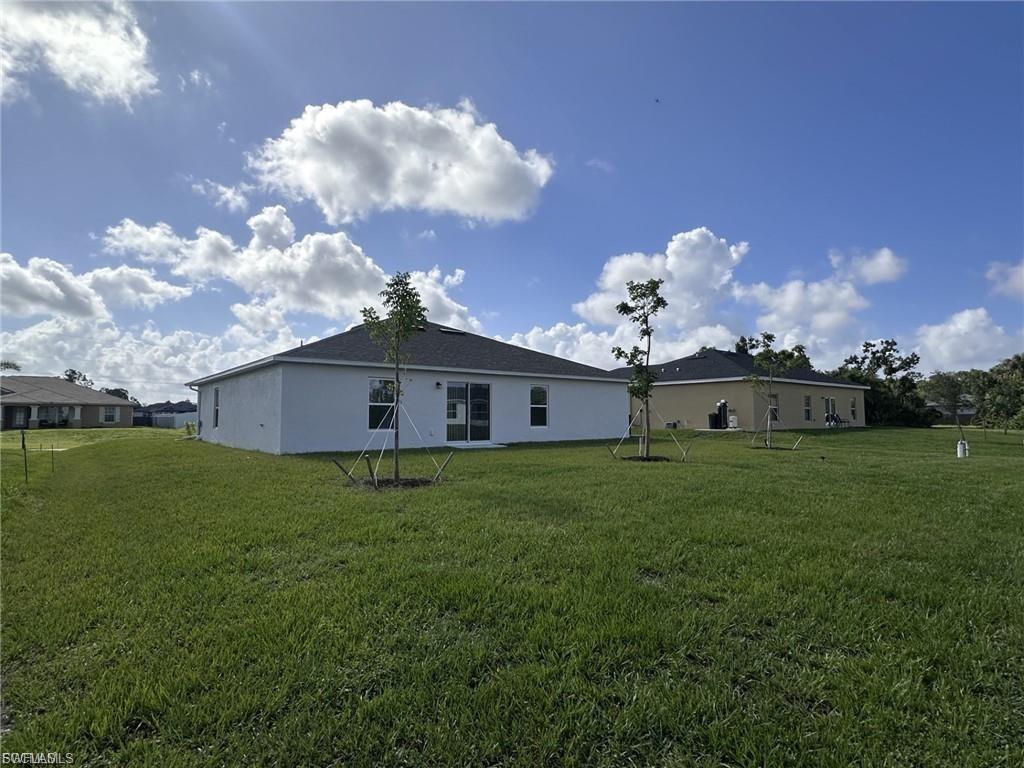 Back of house featuring a yard and stucco siding