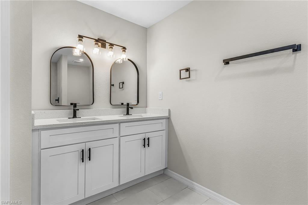 Full bath with double vanity and light tile patterned floors