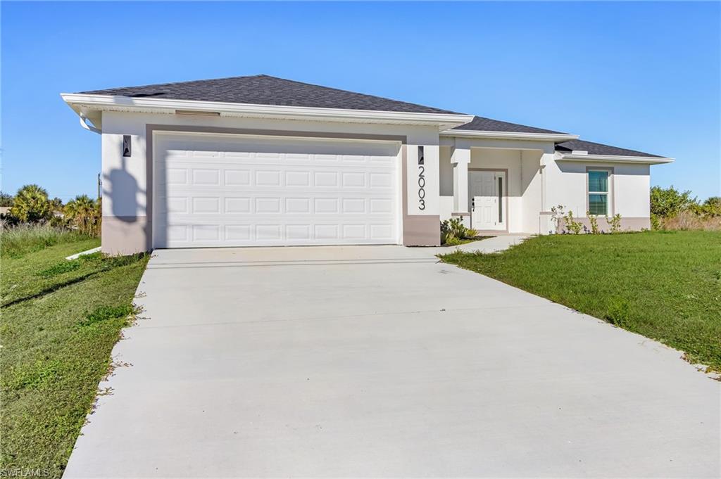 View of front of home featuring a front yard, stucco siding, driveway, and an attached garage