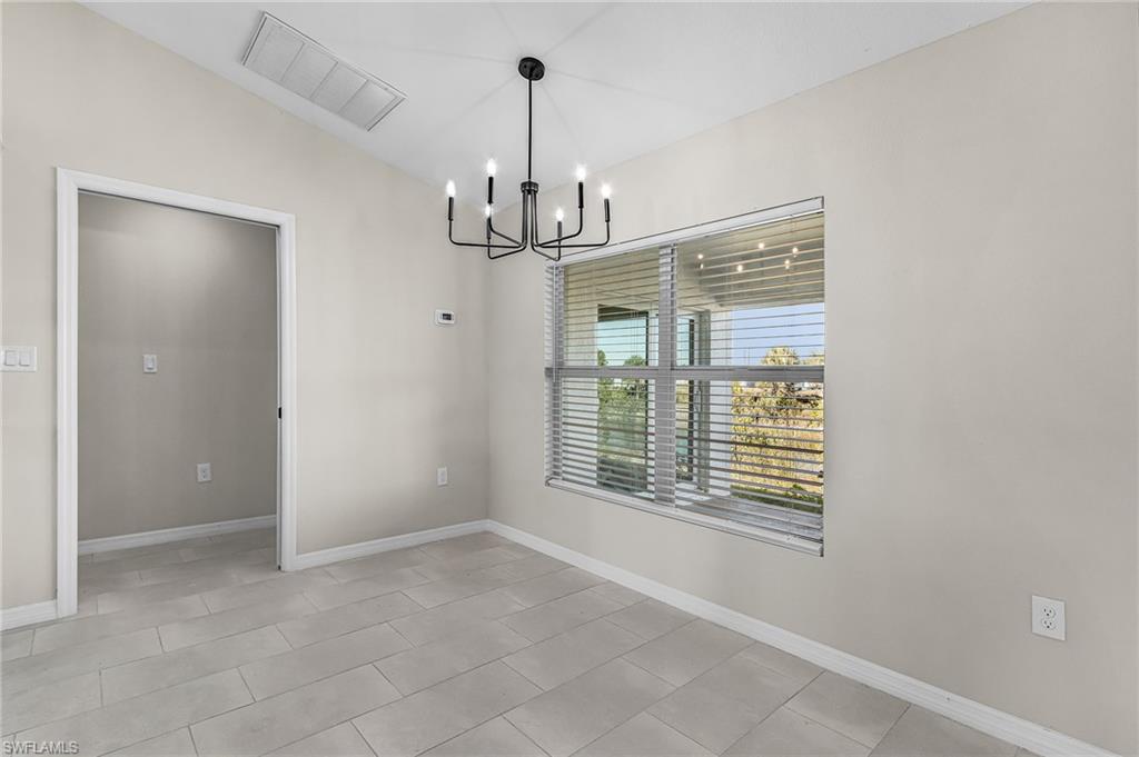 Unfurnished dining area with vaulted ceiling, a chandelier, and light tile patterned flooring