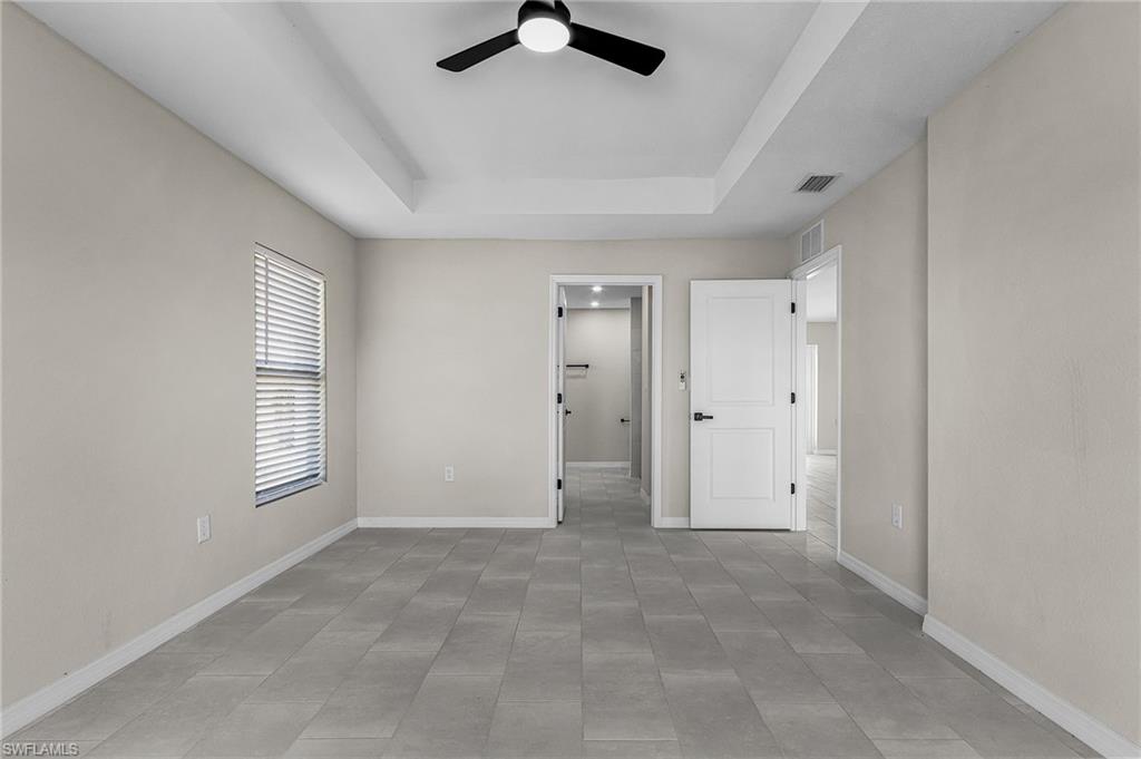 Unfurnished bedroom featuring a ceiling fan and a raised ceiling