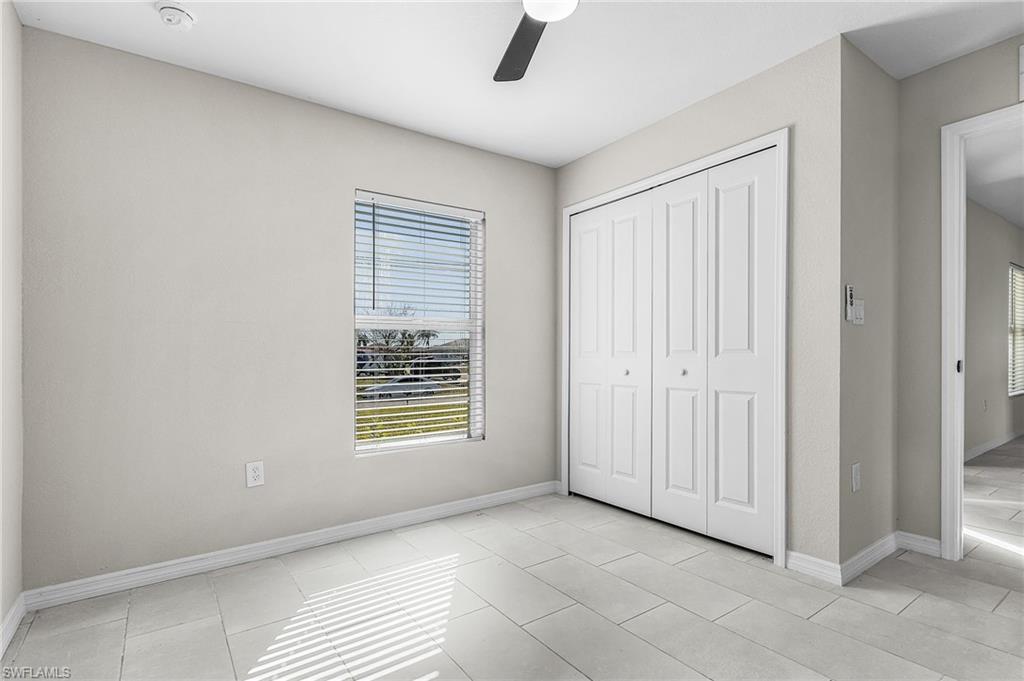 Unfurnished bedroom with ceiling fan, a closet, and light tile patterned floors