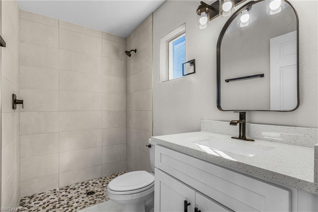 Bathroom with vanity, a stall shower, and a textured wall